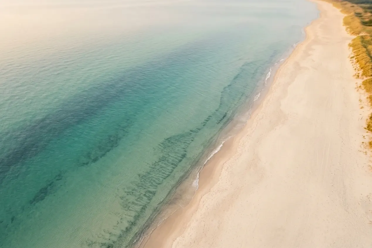 Flaches, warmes Ostseewasser über hellem Sand an einem heißen Sommerabend